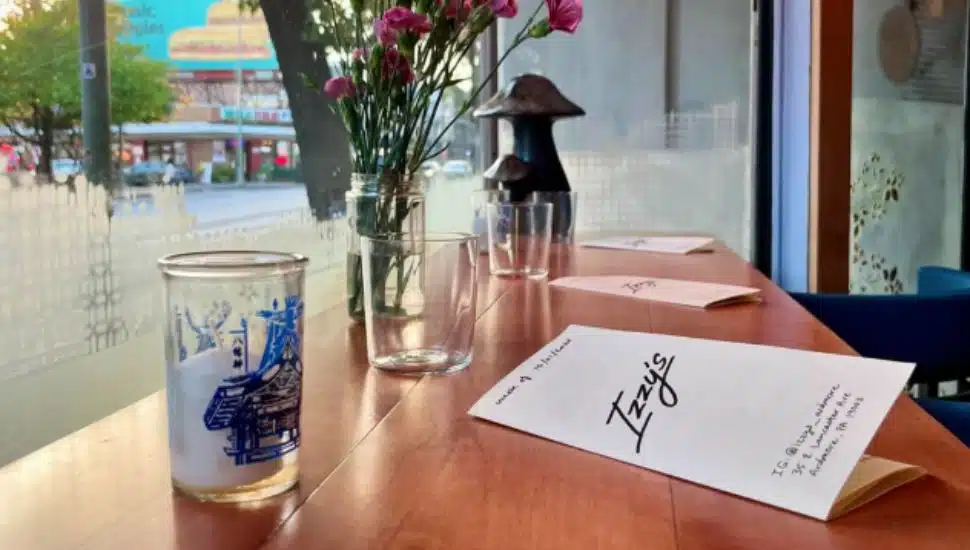 An Izzy's menu and cocktail glass resting on a window-side table.