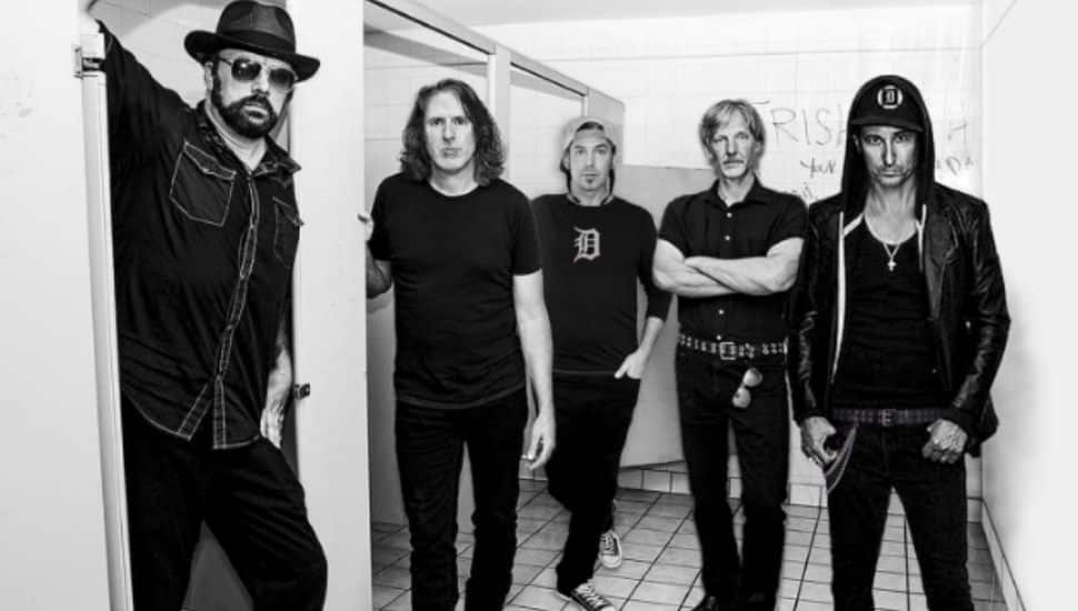 Black and white photo of the band members of sponge, posed in a bathroom. They are wearing dark colors and looking at the camera.