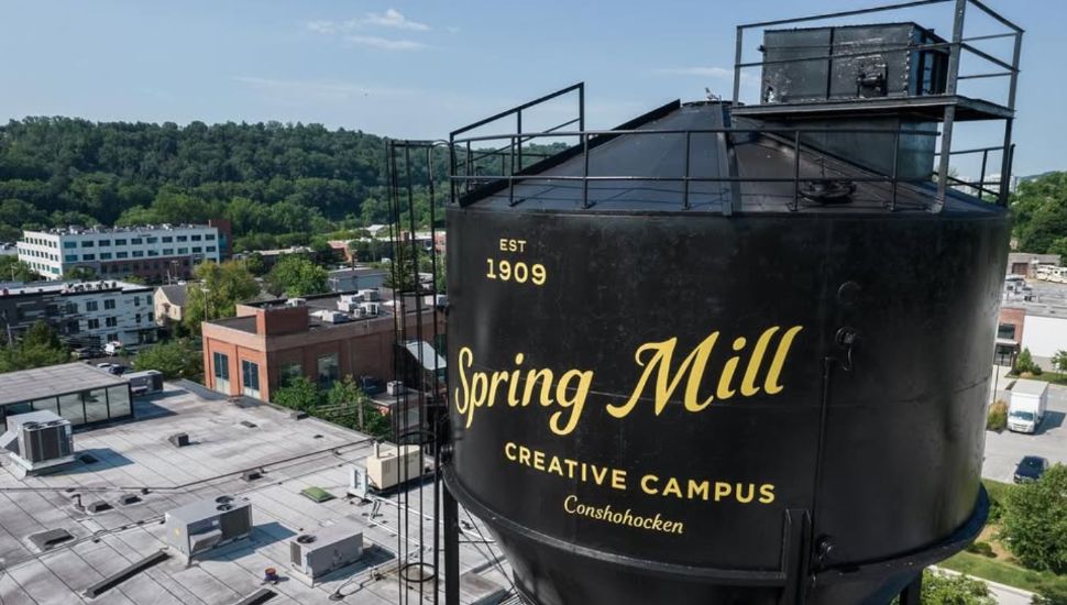 A water tower with the 'Spring Mill Creative Campus in Conshohocken' written in yellow.