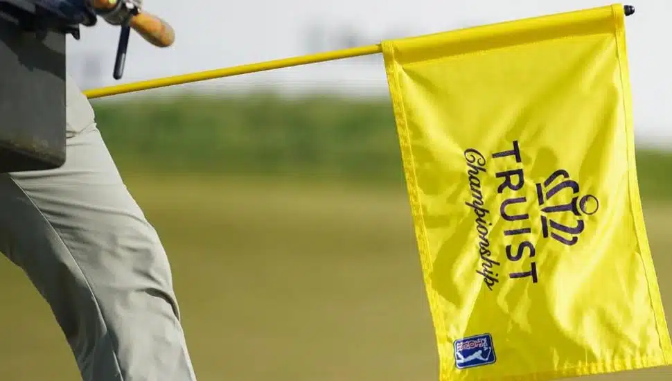 Greenskeeper walking with a Truist Championship flag.