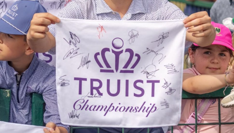 Children spectators hold up an autographed Truist Championship towel.