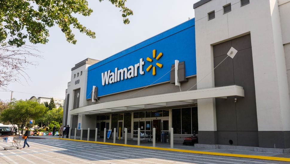 People going in and coming out of a Walmart store on a sunny day.