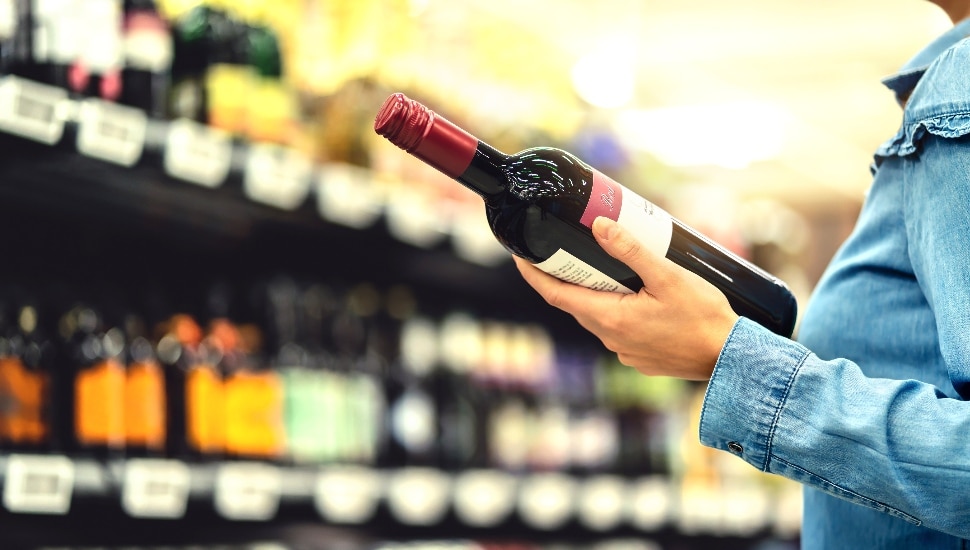 Woman buying a bottle of red wine.