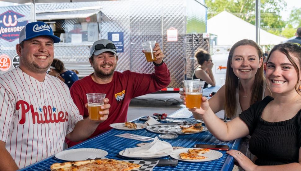 A group of friends raise their beers at the Workhorse Brewing beer garden.