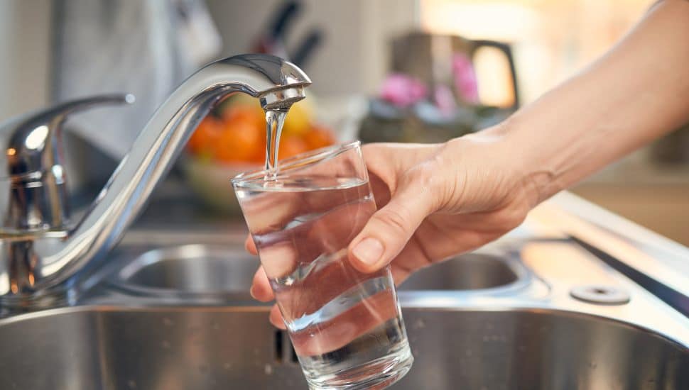 Close up of a hand Pouring Fresh Tap Water Into a Glass