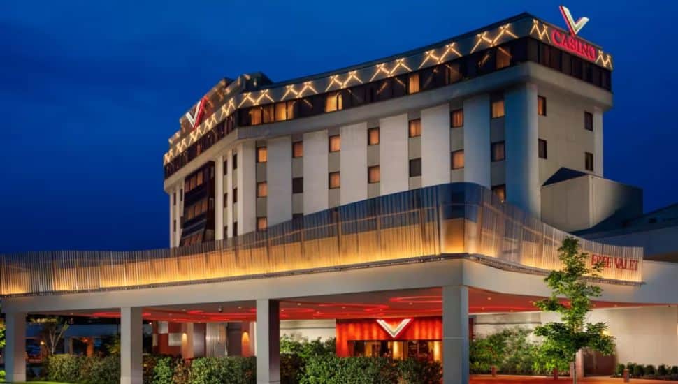 Exterior view of Valley Forge Casino Resort at dusk, featuring modern lighting accents on the upper facade, a brightly lit entrance with red highlights, and signage for free valet service.