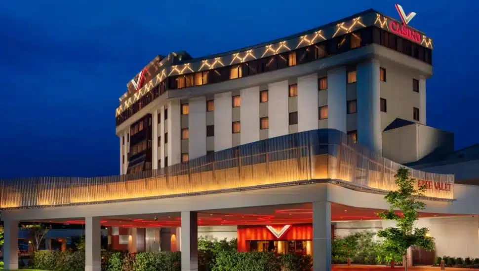 Exterior view of Valley Forge Casino Resort at dusk, featuring modern lighting accents on the upper facade, a brightly lit entrance with red highlights, and signage for free valet service.