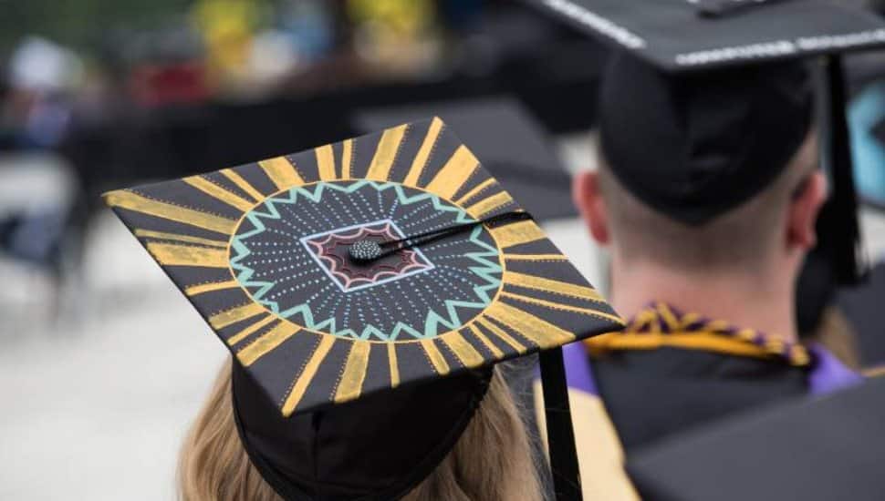 Close up of a graduate's cap from behind. It has been embellished with yellow and purple paint for WCU coloring.