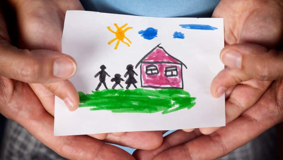 Child and his mom holding a drawn house with family.