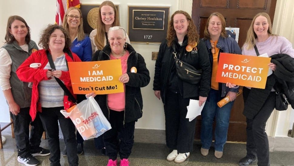 Arc advocates and self-advocates hold signs supporting Medicaid funding meet with staff for Rep. Chrissy Hoolahan.
