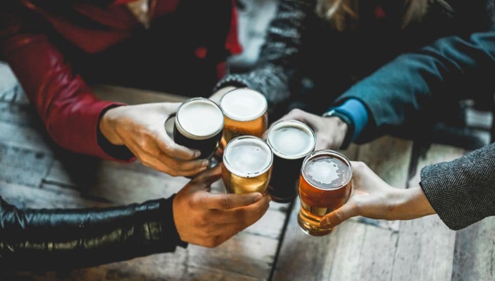 Young group of people having fun cheering with beer.