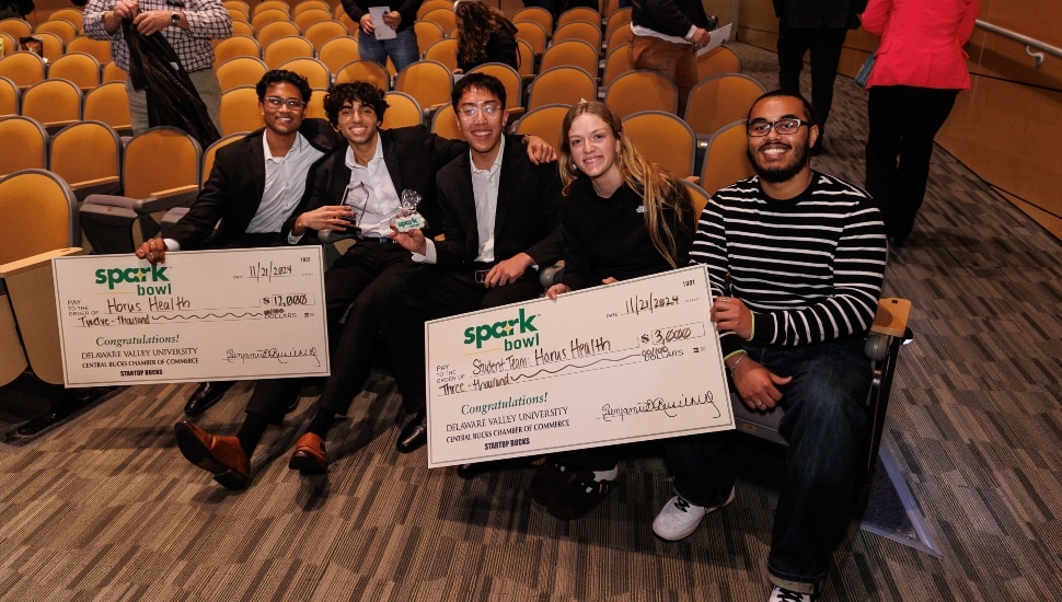 Group photo of entrepreneur contest winners holding big checks.