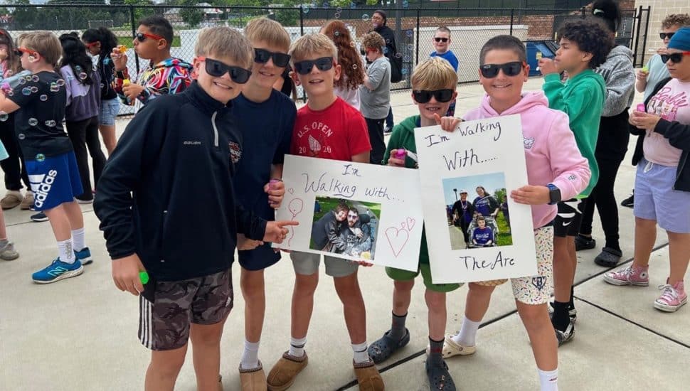 5th Grade students of Greystone Elementary hold up signs and stand in a group celebrating the success of their Mini-Bubble Walk to support The Arc of Chester County.