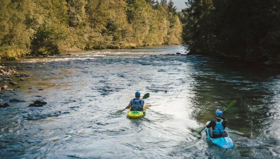 Two men in kayaks, paddling down the Schuylkill River.