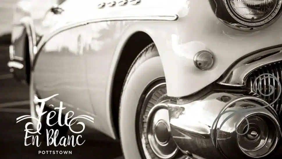 A white classic car with the Fete en Blanc logo.