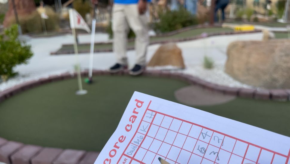A Montgomery County mini golf score card as someone puts in the background.