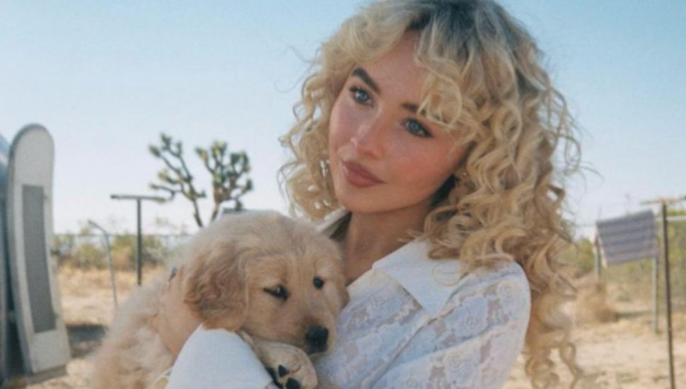 Sabrina Carpenter holds a puppy on the set of her Manchild music video.