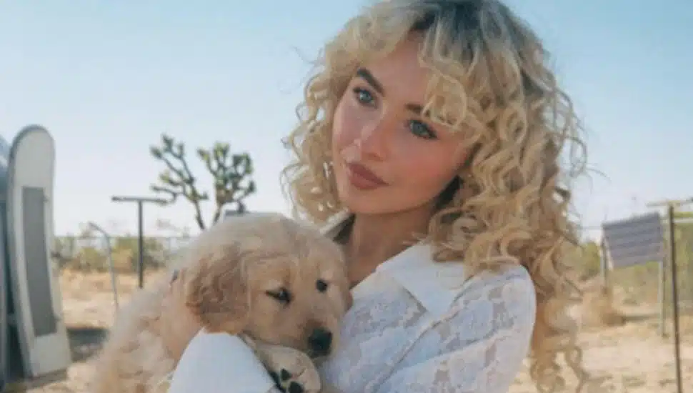 Sabrina Carpenter holds a puppy on the set of her Manchild music video.