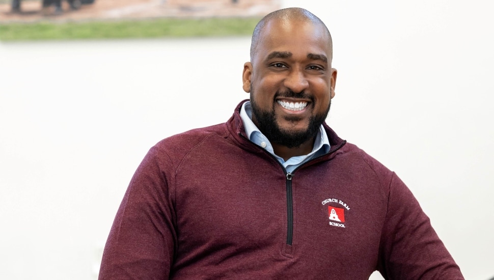 Headshot of smiling, middle-aged head of school in maroon sweater.
