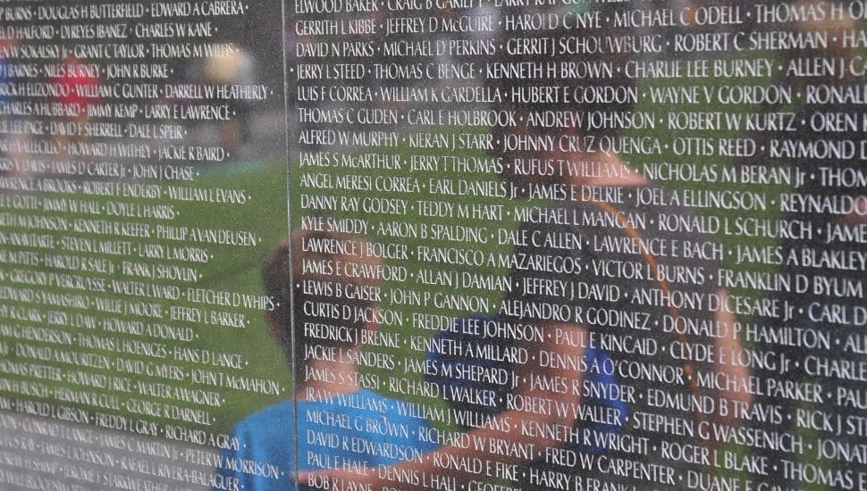 The reflection of a mother and her son against the Vietnam War Memorial.