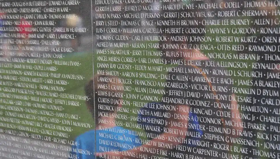 The reflection of a mother and her son against the Vietnam War Memorial.