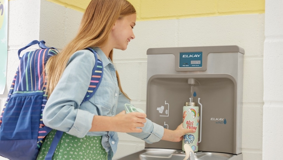A young girl using an Elkay water bottle filling station