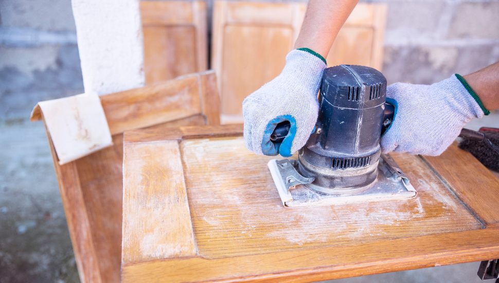 Person sanding down cabinets.