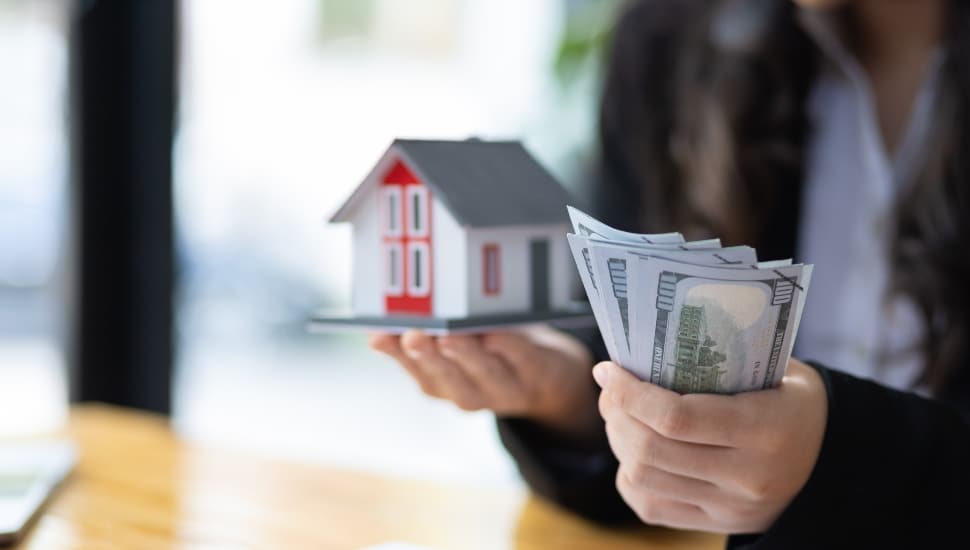Real estate agent holding house and deposit.