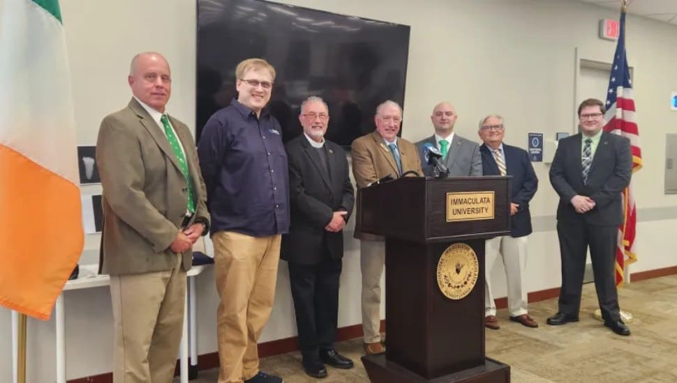Group of researchers stand at podium with Irish and American flags behind them.