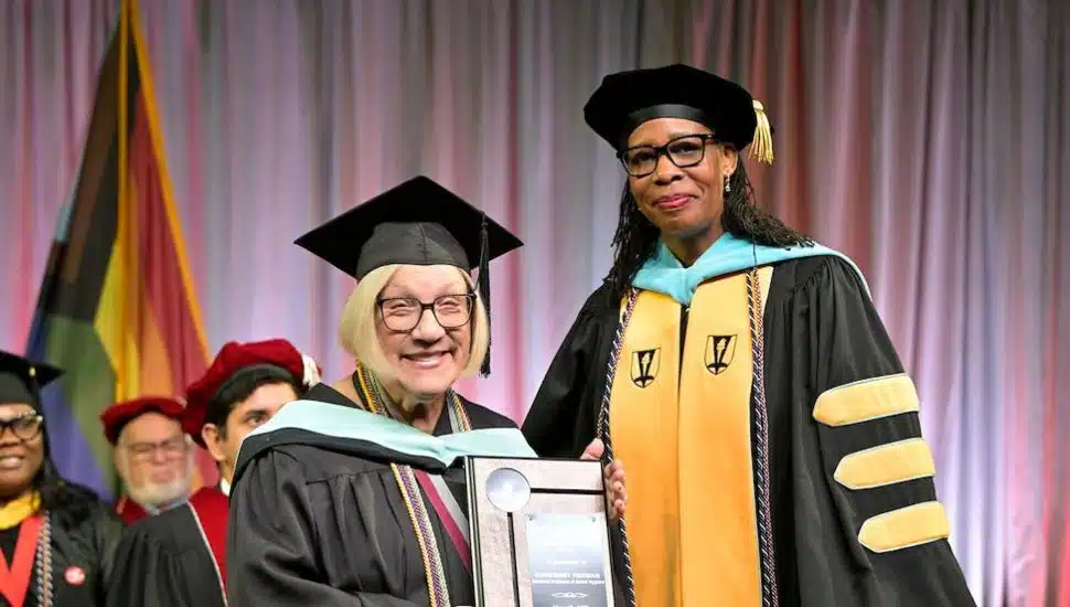 An image of Gladys and Raymond Pearlstine Teaching Excellence Award recipient Rosemary Herman, Dental Hygiene Assistant Professor, and Dr. Chae Sweet, Vice President of Academic Affairs and Provost. They wear cap and gown and are standing on stage at MCCC.