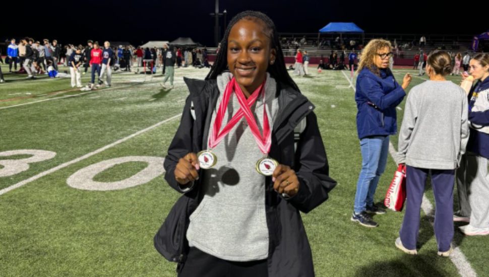 Destini Smith on the track wearing two medals.