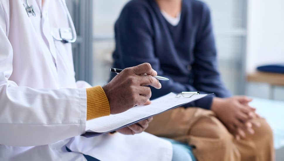 A doctor holding clipboard while consulting child in clinic.