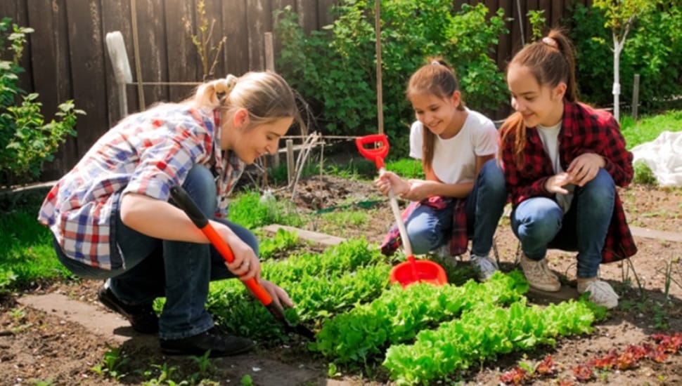 Woman works in a garden with her two daughters.