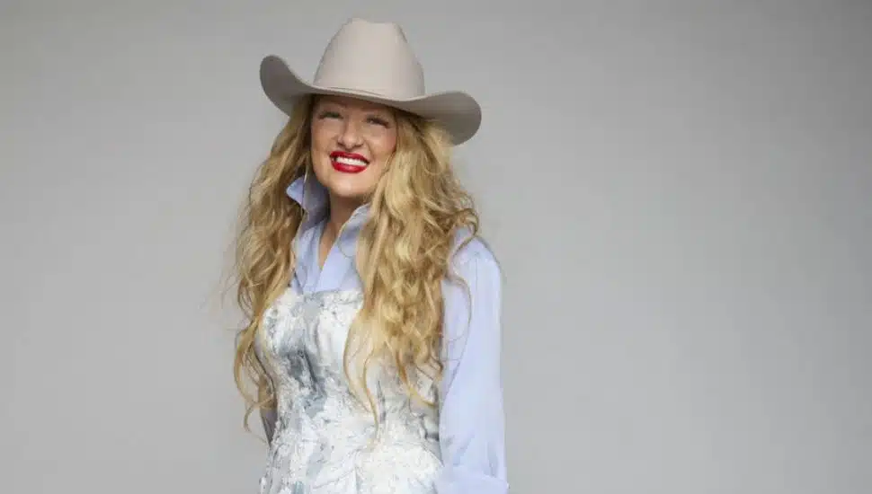 David's Bridal CEO Kelly Cook is wearing a dress and a cowboy hat.
