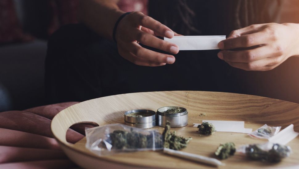 A man rolls marijuana into a joint.