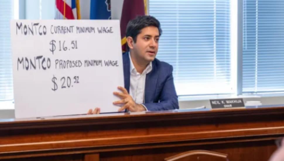 Commissioner Neil Makhija holds a sign discussing the proposed Montgomery County Minimum Wage.