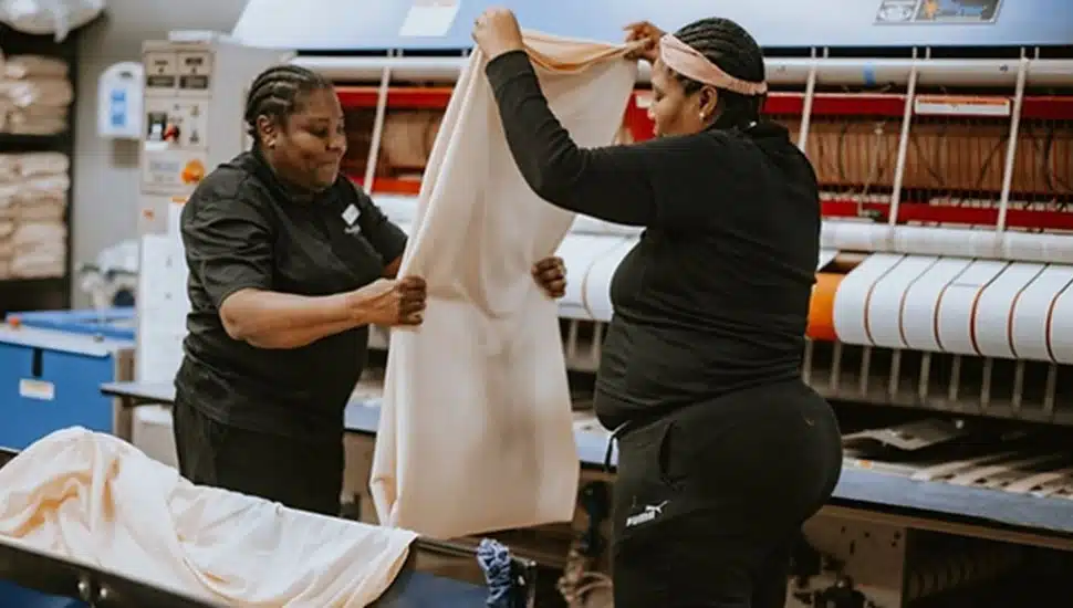 Two hotel workers fold linens.