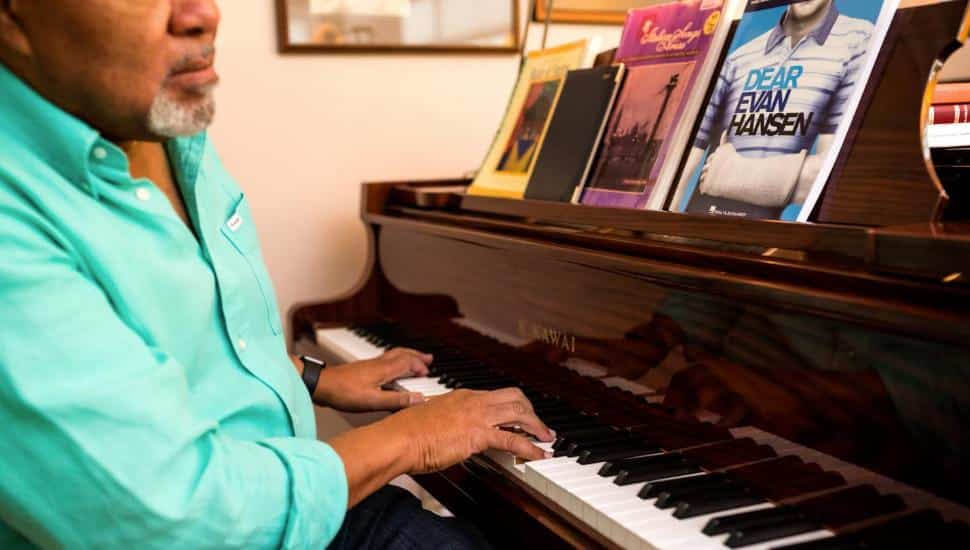 Paul Spencer Adkins sits at his piano with sheet music from the Broadway show Dear Evan Hansen.