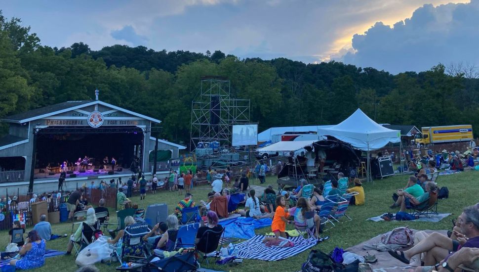 Attendees sprawl out on a hill overlooking the Philadelphia Folk Festival stage.