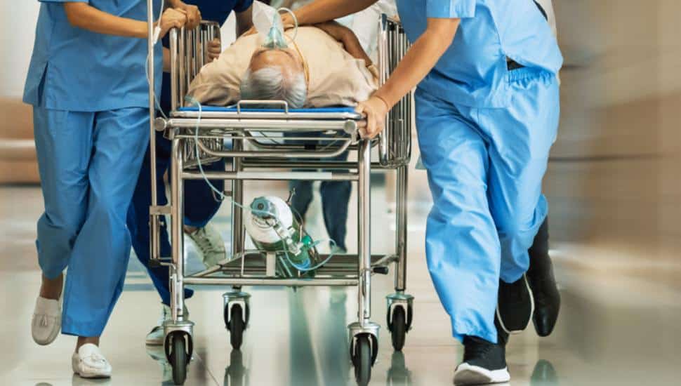 Group of Doctors, Nurses, Paramedics Push Gurney, Stretcher with Seriously trauma Patient towards the Operating Room.