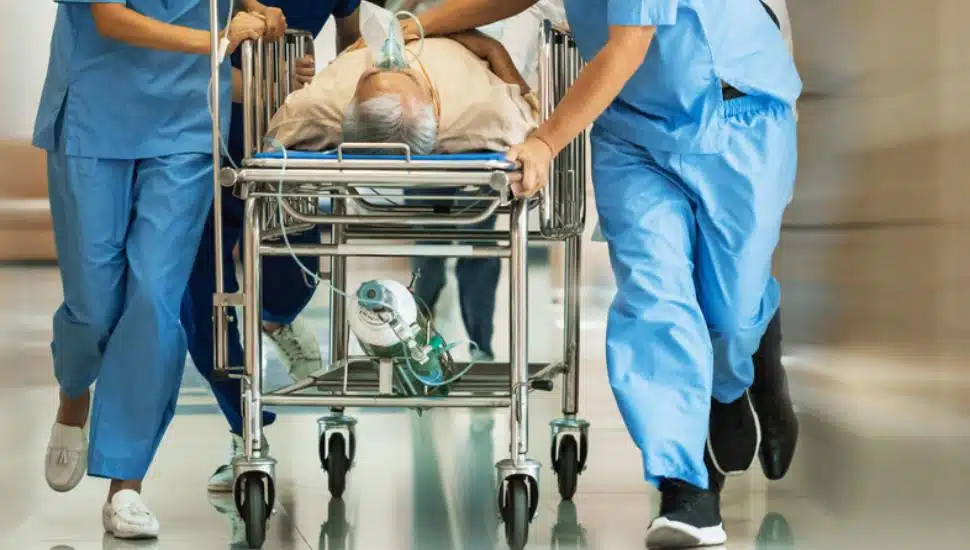 Group of Doctors, Nurses, Paramedics Push Gurney, Stretcher with Seriously trauma Patient towards the Operating Room.