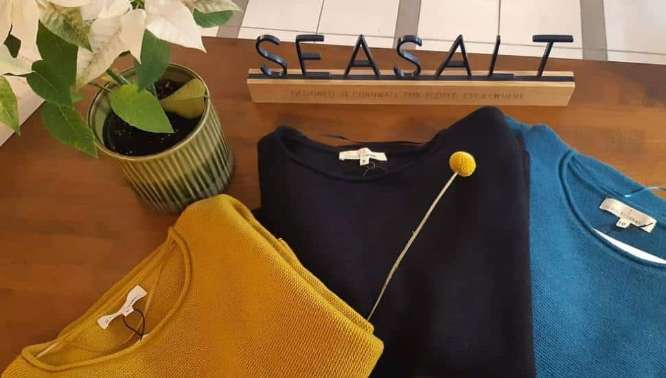 Sweaters sit on a table with signage for Seasalt Cornwall.