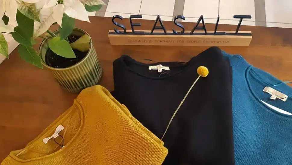 Sweaters sit on a table with signage for Seasalt Cornwall.