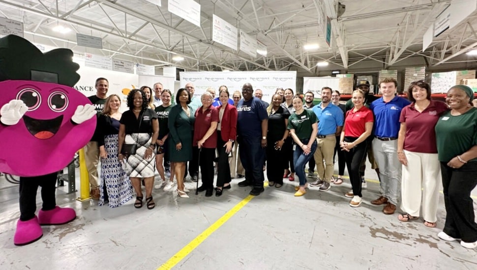 Credit union representatives pose for group picture with hunger relief agency mascot.