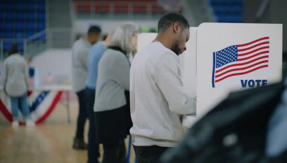 Multicultural American citizens come to vote in polling station.