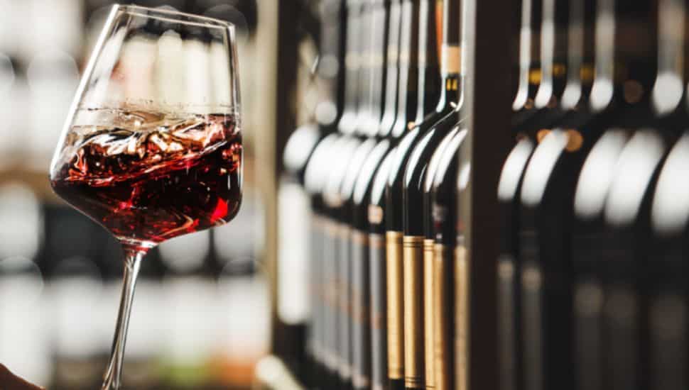 Close up shot of person hand as they swirl a glass of red wine.