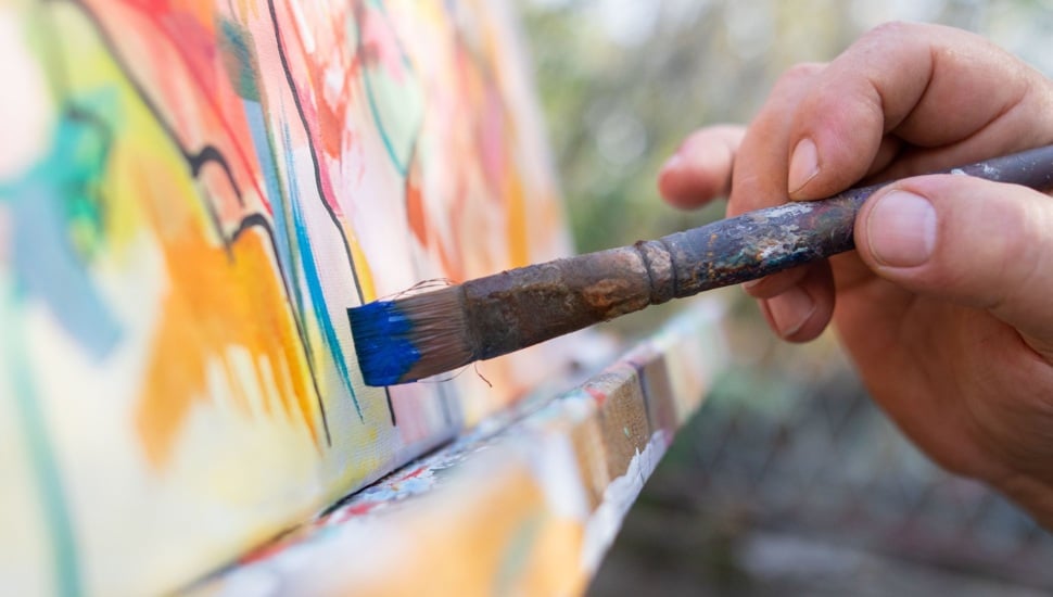 Close-up of an artist working on painting in studio.
