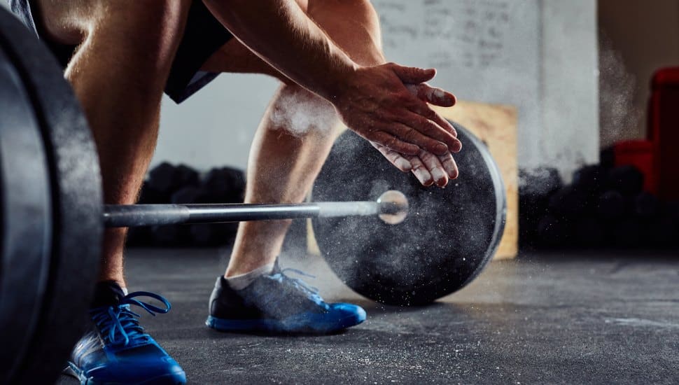 Closeup of weightlifter clapping hands before barbell workout.