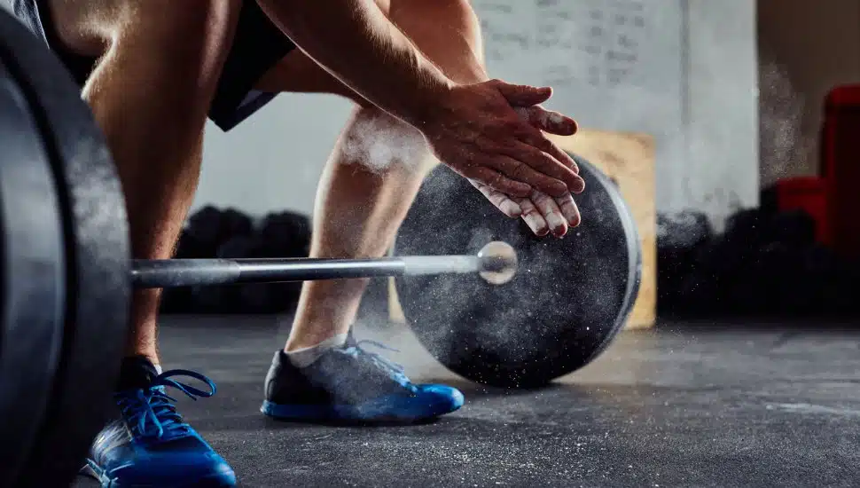 Closeup of weightlifter clapping hands before barbell workout.