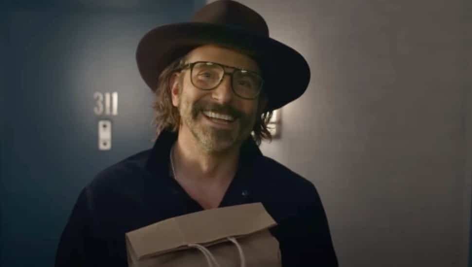 Bradley Cooper comes to the front door in glasses and a hat in the film, Is This Thing On?